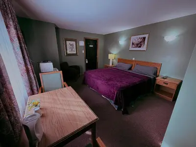 a bedroom with a purple bed and a table at Guest Inn Motel in Trenton