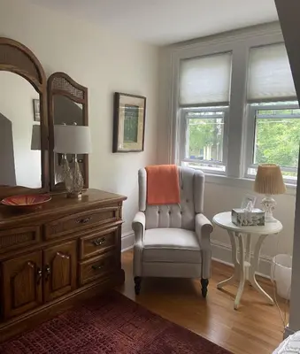 a bedroom with a chair and a dresser and a mirror at Cottage on Caledonia Bed & Breakfast in Stratford