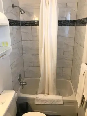 a bathroom with a shower with a tub and a toilet at All Seasons Motel in Port Elgin
