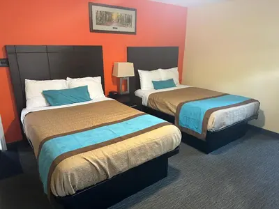 two beds in a hotel room with orange walls at All Seasons Motel in Port Elgin