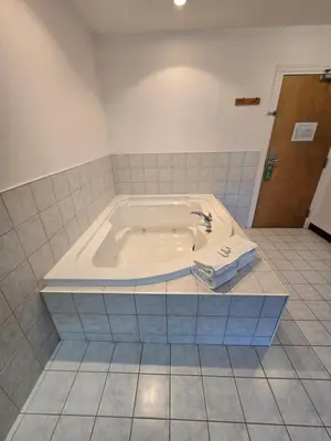 a bath tub in a bathroom with a tile floor at Travelodge by Wyndham Port Elgin in Port Elgin