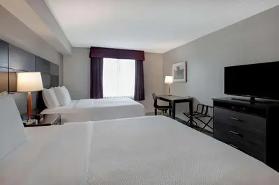 a hotel room with two beds and a flat screen tv at Days Inn & Suites by Wyndham Collingwood in Collingwood