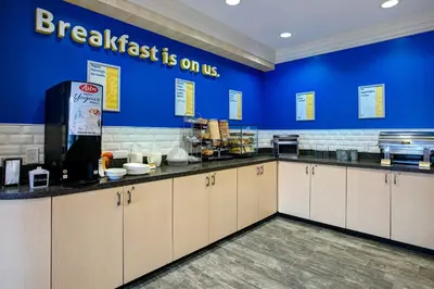 a kitchen with a breakfast is on us sign on the wall at Days Inn & Suites by Wyndham Collingwood in Collingwood