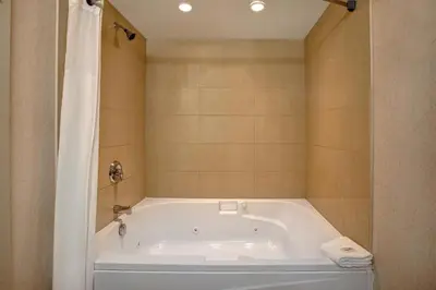 a white bath tub in a bathroom with a shower at Days Inn & Suites by Wyndham Collingwood in Collingwood