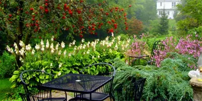 a garden with a table and chairs and flowers at Historic Lyons House in Niagara on the Lake