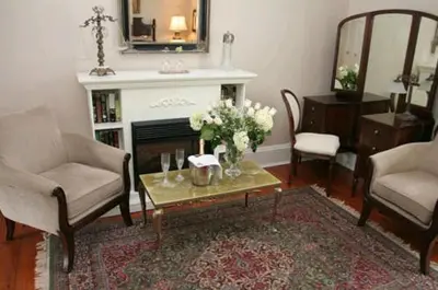 a living room with a fireplace and a table with flowers at Historic Lyons House in Niagara on the Lake
