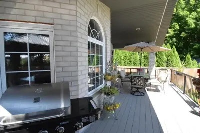 a deck with a grill and an umbrella at Graystone Bed & Breakfast in Niagara on the Lake
