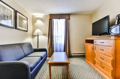 a living room with a couch and a tv at Best Western Plus Cambridge Hotel in Cambridge