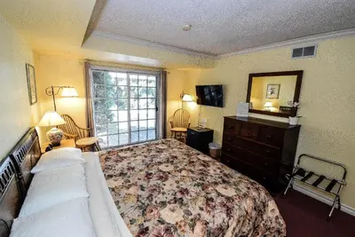 a bedroom with a bed and a dresser and a window at Blairpen House Country Inn in Niagara on the Lake