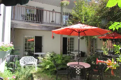 a patio with tables and chairs and an umbrella at Blairpen House Country Inn in Niagara on the Lake