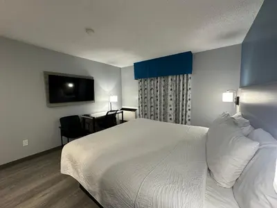 a bedroom with a large white bed and a desk at Travelodge by Wyndham Bracebridge in Bracebridge