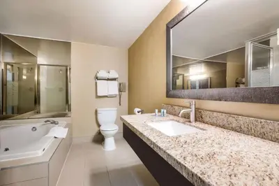 a bathroom with a sink and a toilet and a bath tub at Best Western Little River Inn in Simcoe