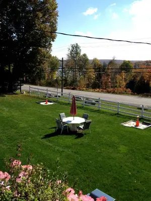 a table and chairs with an umbrella on the grass at Lakeview Motel in Haliburton