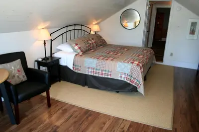 a bedroom with a bed and a chair and a mirror at Hadovka Lakeside Inn in Wellington