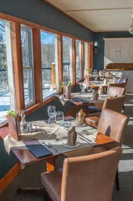 a dining room with tables and chairs and windows at Heather Lodge in Minden