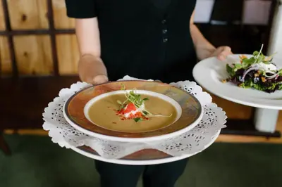 a person holding a bowl of soup on a plate at Heather Lodge in Minden