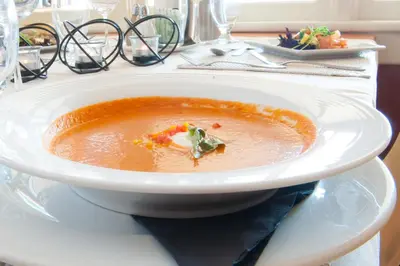 a bowl of soup on a plate on a table at Heather Lodge in Minden