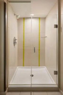 a shower with a tub and a yellow stripe on the wall at SpringHill Suites by Marriott Toronto Vaughan in Vaughan