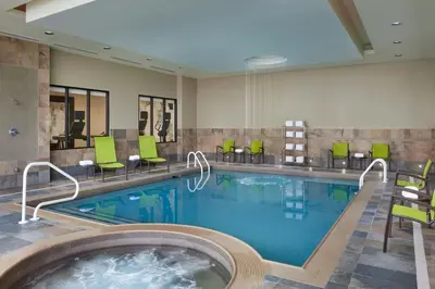 a hotel room with a large swimming pool with green chairs at SpringHill Suites by Marriott Toronto Vaughan in Vaughan
