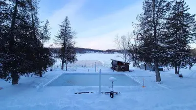 a swimming pool covered in snow next to trees at Bonnie View Inn in Haliburton