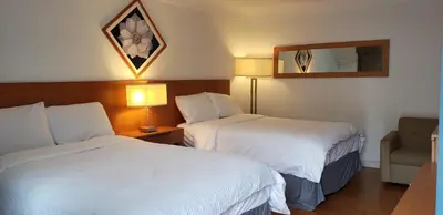 a hotel room with two beds and a mirror at Niagara Inn in Niagara Falls