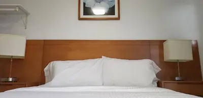 a bedroom with a bed with white sheets and two lamps at Niagara Inn in Niagara Falls