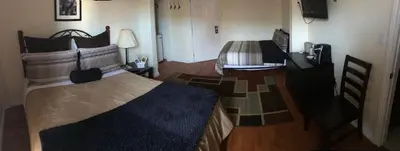 a bedroom with two beds and a desk with a television at Dominion Hotel in Minden