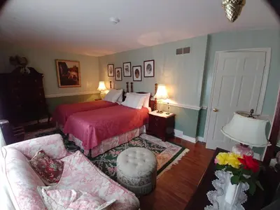 a bedroom with a red bed and a couch at TwiningRetreat in Niagara on the Lake