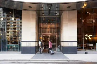 two people standing outside of a building with their luggage at Le Germain Hotel Toronto in Toronto