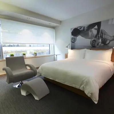 a bedroom with a large bed and a chair at Le Germain Hotel Maple Leaf Square in Toronto