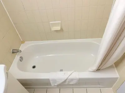 a white bath tub in a bathroom with a shower curtain at Liberty Inn in Bowmanville