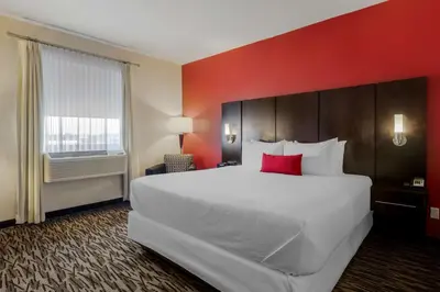 a large white bed in a hotel room with a red wall at C Hotel by Carmen's, BW Premier Collection in Hamilton