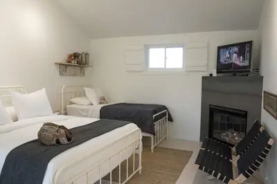 a white room with two beds and a fireplace at The Lakeside Prince Edward County in Wellington