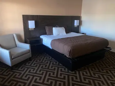 a bedroom with a large bed and a chair at Falls Lodge by the Falls (Formerly Knights Inn) in Niagara Falls
