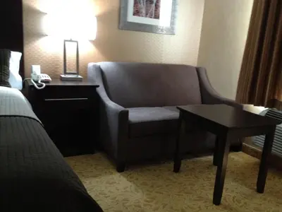 a living room with a chair and a table in a hotel room at Mississauga Gate Inn in Mississauga