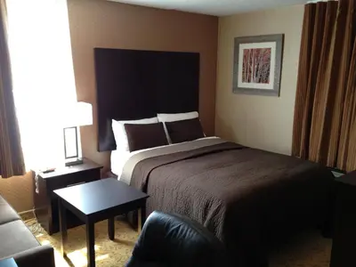 a hotel room with a bed and a chair at Mississauga Gate Inn in Mississauga