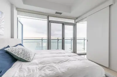 a bedroom with a large bed with glass windows at Executive Corner Suite with Panoramic View in Toronto