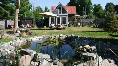a man and woman sitting under an umbrella near a pond at Four Ninety Muskoka B & B in Gravenhurst