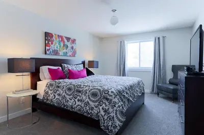 a bedroom with a black and white bed with pink pillows at Boardwalk Homes - Executive Guest Rooms & Townhomes in Kitchener