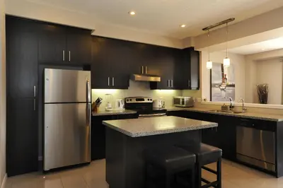 a kitchen with black cabinets and a stainless steel refrigerator at Boardwalk Homes - Executive Guest Rooms & Townhomes in Kitchener