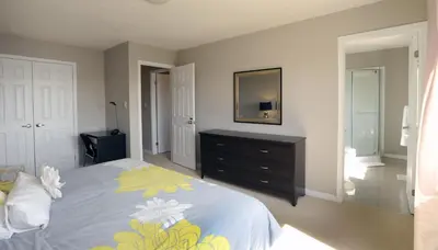 a bedroom with a bed with a dresser and a mirror at Boardwalk Homes - Vacation Homes & Executive Suites in Kitchener
