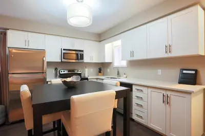 a kitchen with white cabinets and a black table at Boardwalk Homes - Vacation Homes & Executive Suites in Kitchener