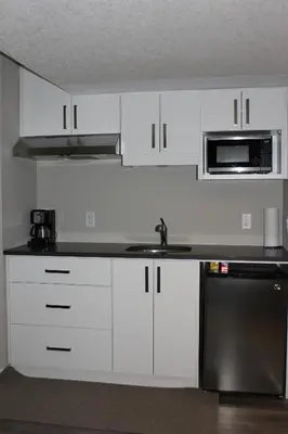 a kitchen with white cabinets and a sink and a microwave at Boardwalk Homes - Vacation Homes & Executive Suites in Kitchener