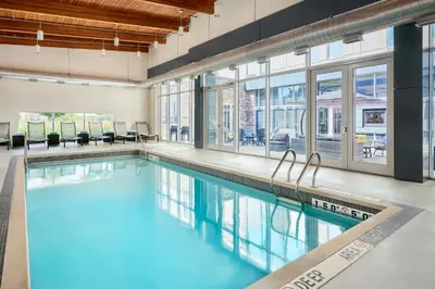 a swimming pool with blue water in a building with windows at Aloft Vaughan Mills in Vaughan
