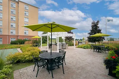 a patio with a table and chairs and an umbrella at Homewood Suites by Hilton Toronto Oakville in Oakville