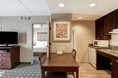 a kitchen with a table and a room with a bed at Homewood Suites by Hilton Toronto Oakville in Oakville