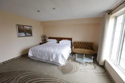 a bedroom with a bed and a chair and a window at Fullerton Manor Inn in Niagara Falls