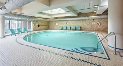 a pool in a large room with green chairs at The Falls Hotel & Inn in Niagara Falls