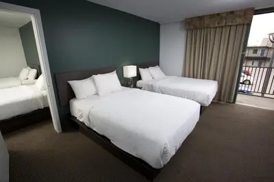 a hotel room with two beds and a balcony at The Falls Hotel & Inn in Niagara Falls