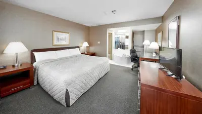 a hotel room with a bed and a flat screen tv at The Falls Hotel & Inn in Niagara Falls
